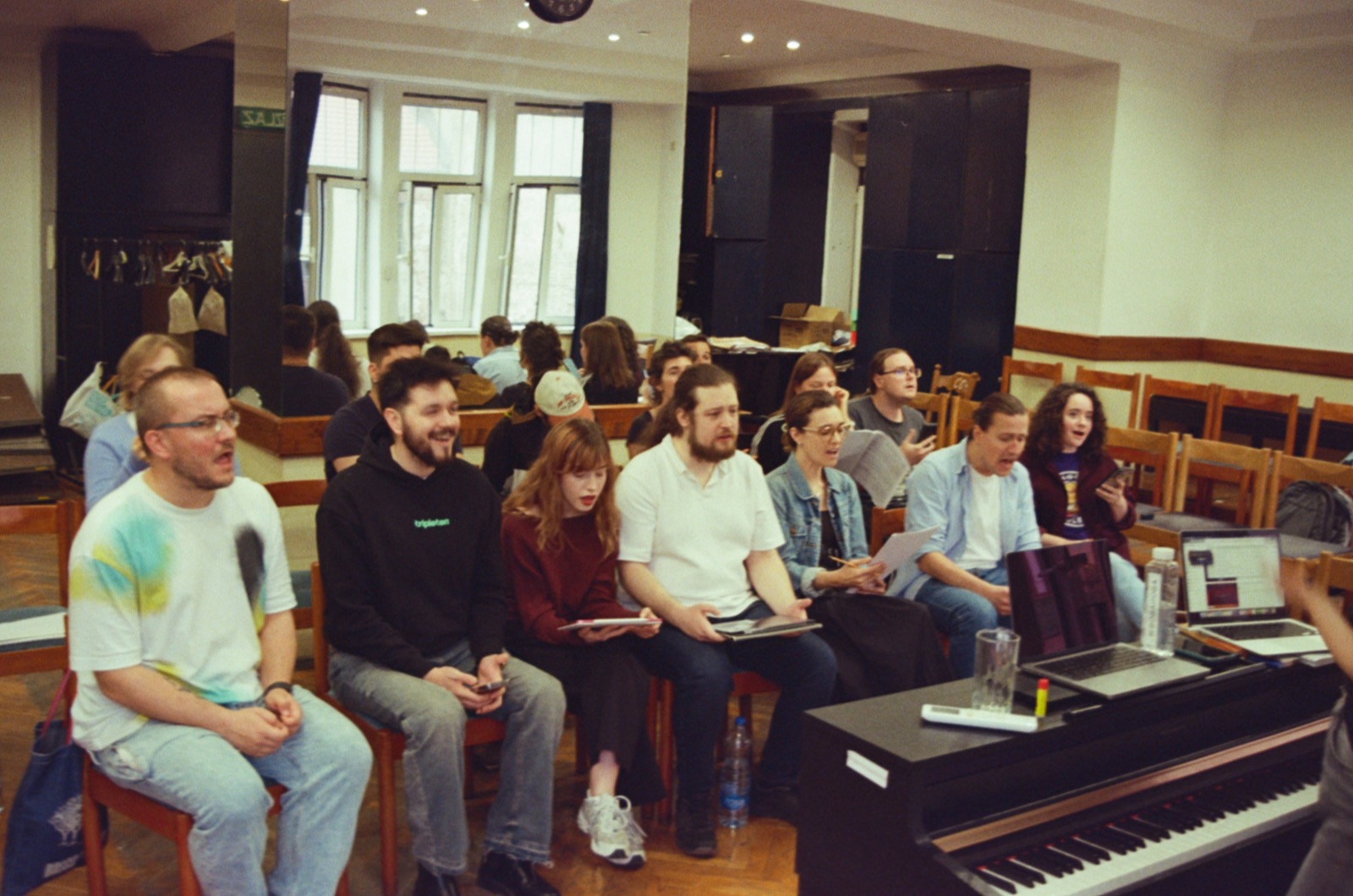 Kuraž members reading music around a piano